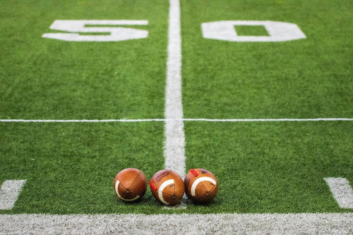 three-footballs-on-football-field-at-50-yard-line
